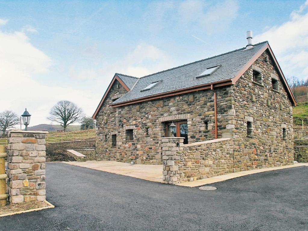 a stone building with a roof on a road at Bwythyn Cerrig in Crynant