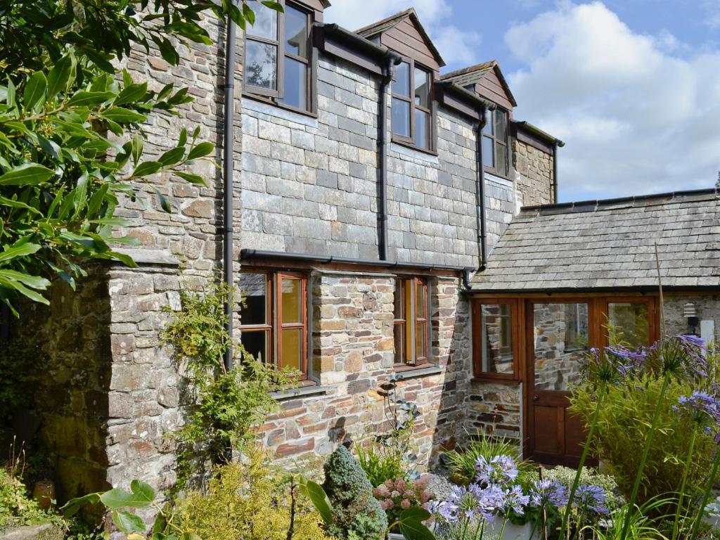 an old stone house with a garden in front of it at Tucked Away in Linkinhorne