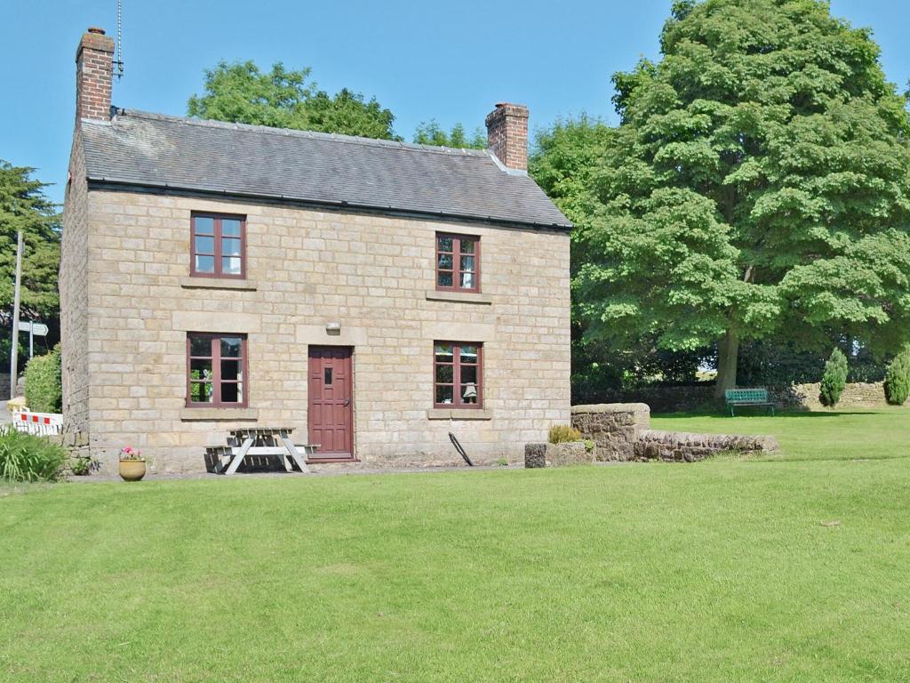 a brick house with a picnic table in a yard at Holly Bank in Crich