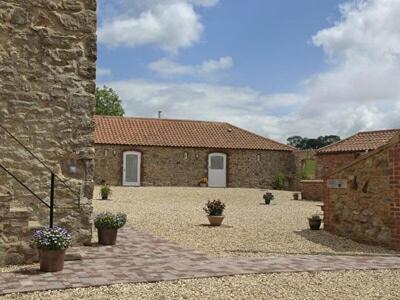 a stone building with potted plants in a courtyard at The Old Dairy - 26726 in North Willingham