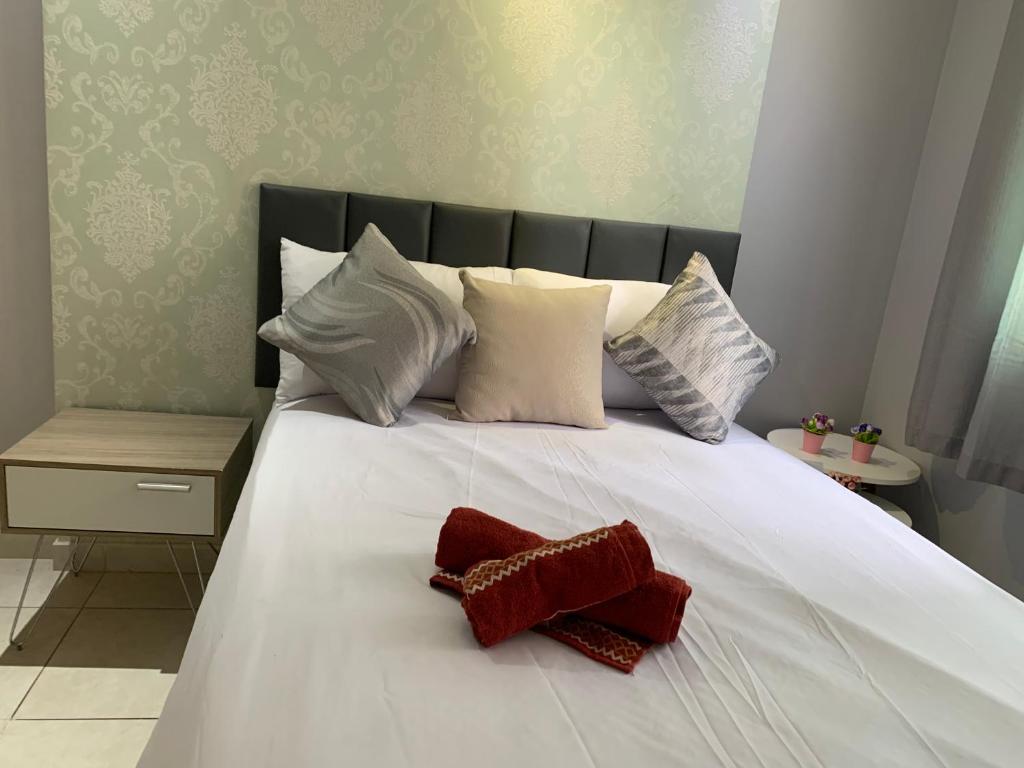 Una cama blanca con almohadas blancas y un objeto rojo. en Apt de 1 quarto em águas claras, en Brasilia