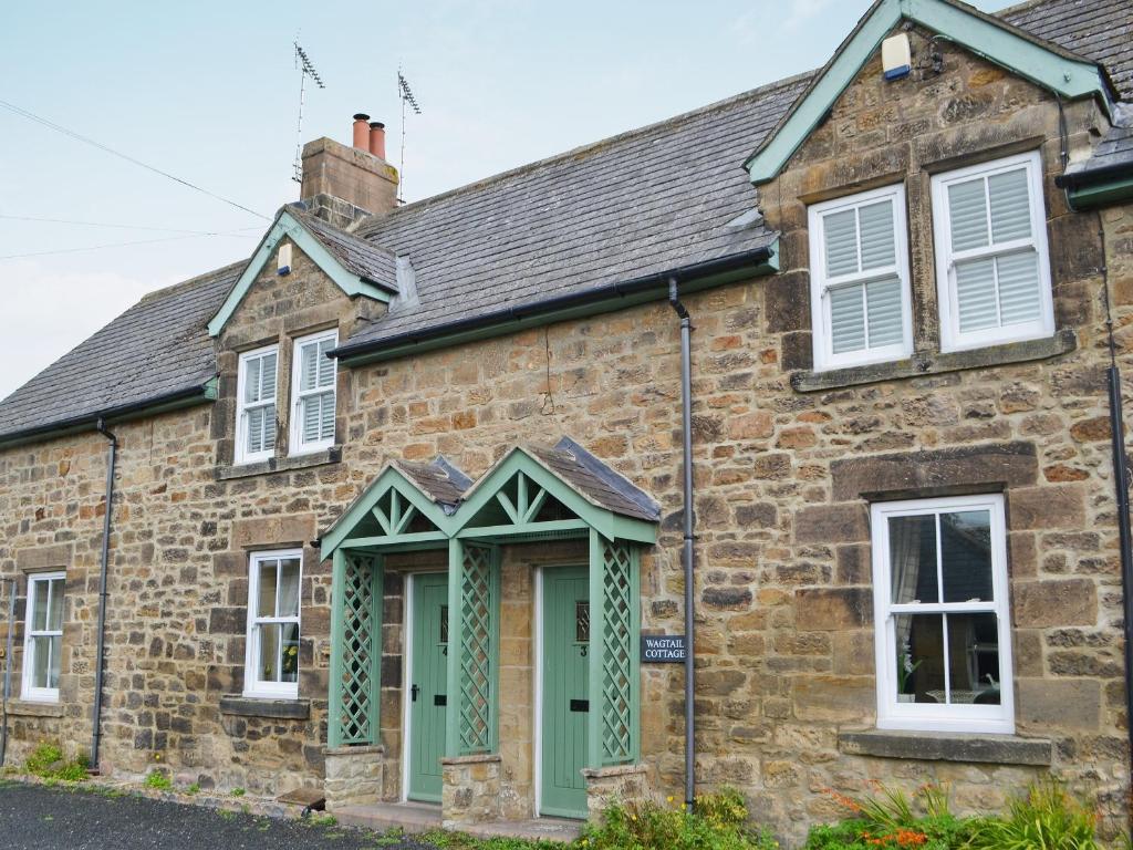 an old stone house with a green door at Wagtail Cottage in Lesbury