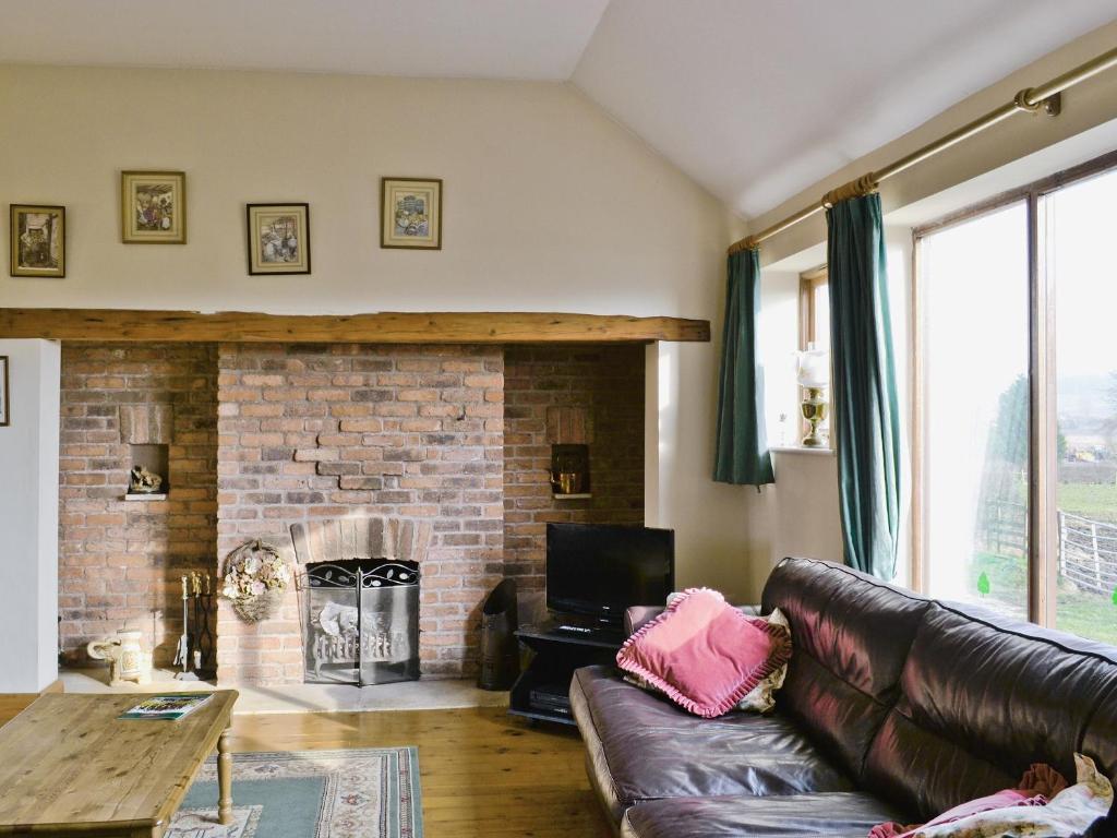 a living room with a leather couch and a fireplace at Ye Olde Smithy in Burythorpe