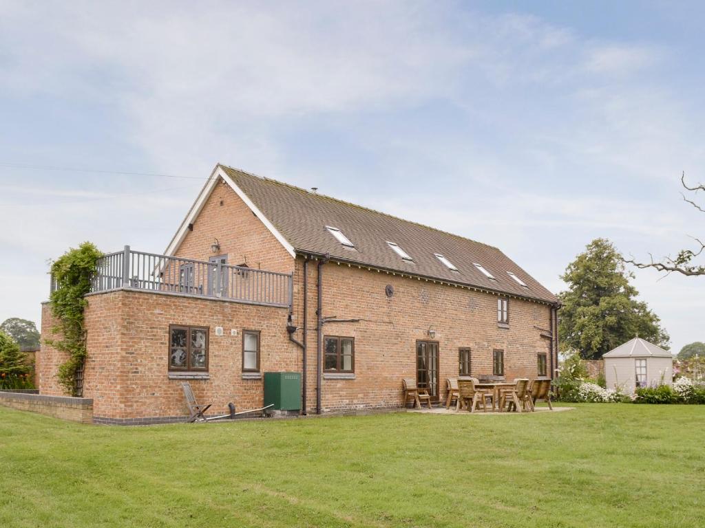 an old brick house with a balcony and tables at Buddileigh Farm in Betley