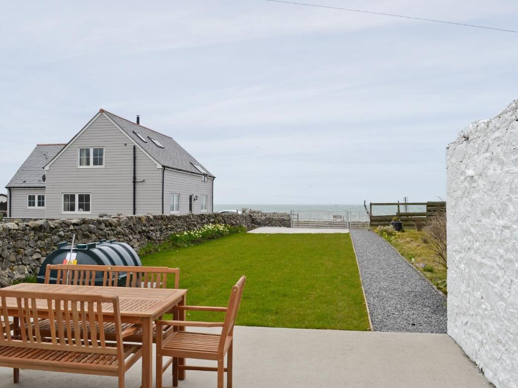 a patio with two benches and a table and a house at Sea-esta - 28175 in Port William