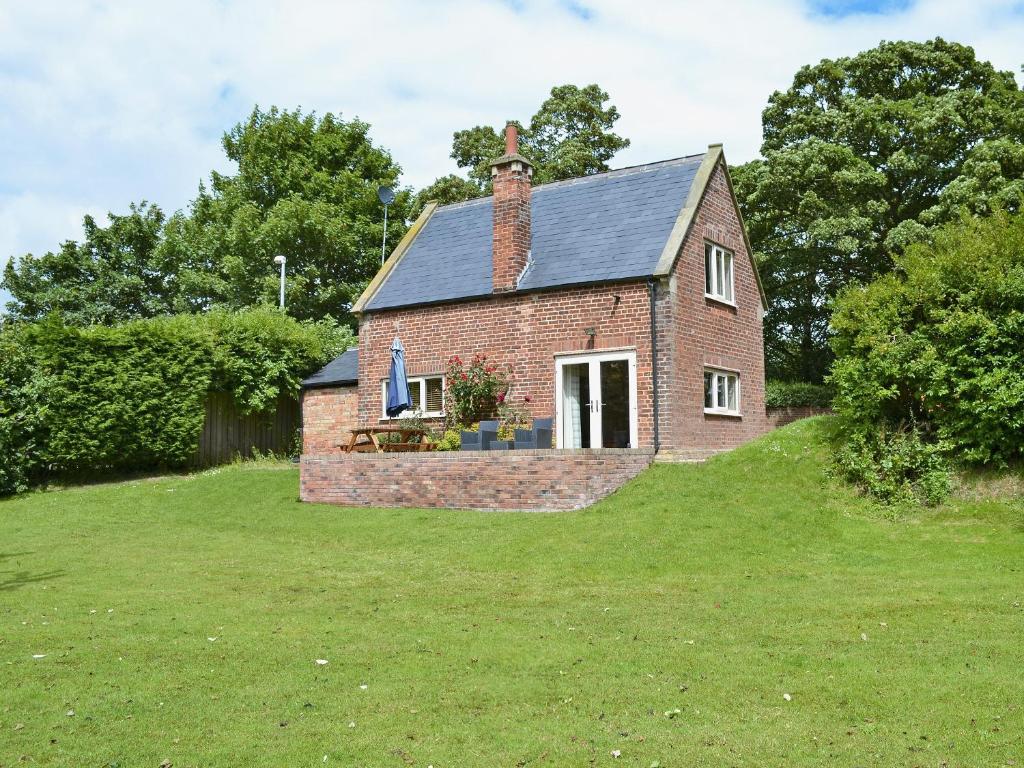 a small brick house on a grassy hill at The Old Coach House in Ulrome