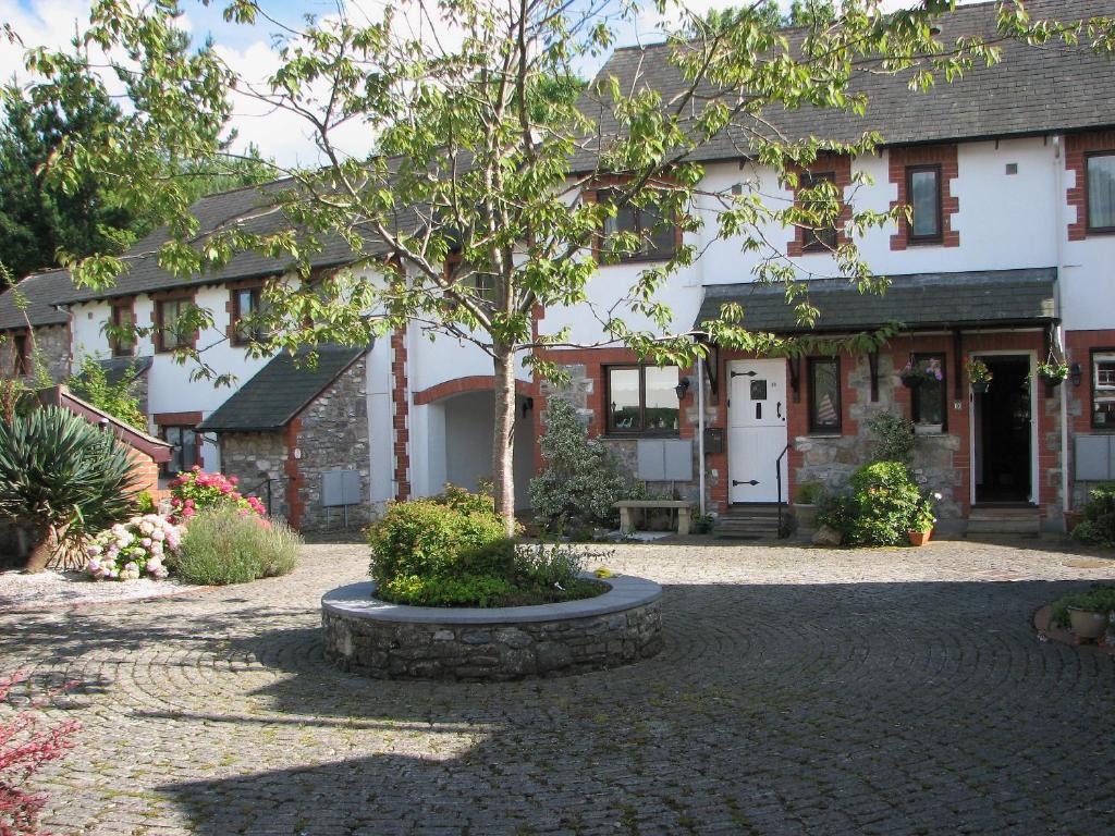 a large white house with a tree in a courtyard at Kays Cottage in Buckfastleigh