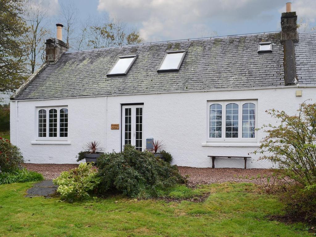 a white house with a bench in front of it at Culcharry Cottage in Cawdor