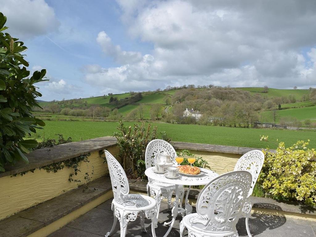 a table and chairs on a patio with a view of a field at Lower Mill Barn in Nantgaredig