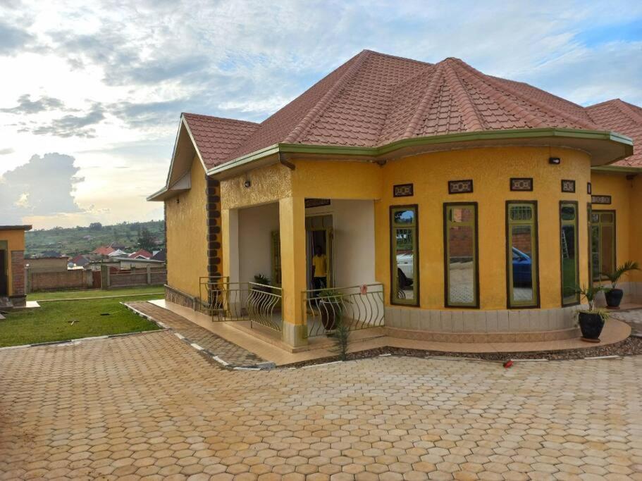 una pequeña casa amarilla con techo de baldosa en Cheerful Villa Nyamata, en Kayenzi