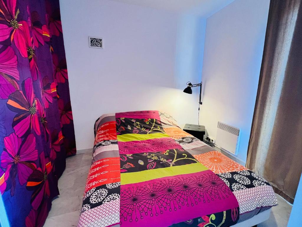 - une chambre avec un lit doté d'une couette colorée dans l'établissement Les Appartements De Lina - Studio Tortue - Self Check-In, à La Grande Motte