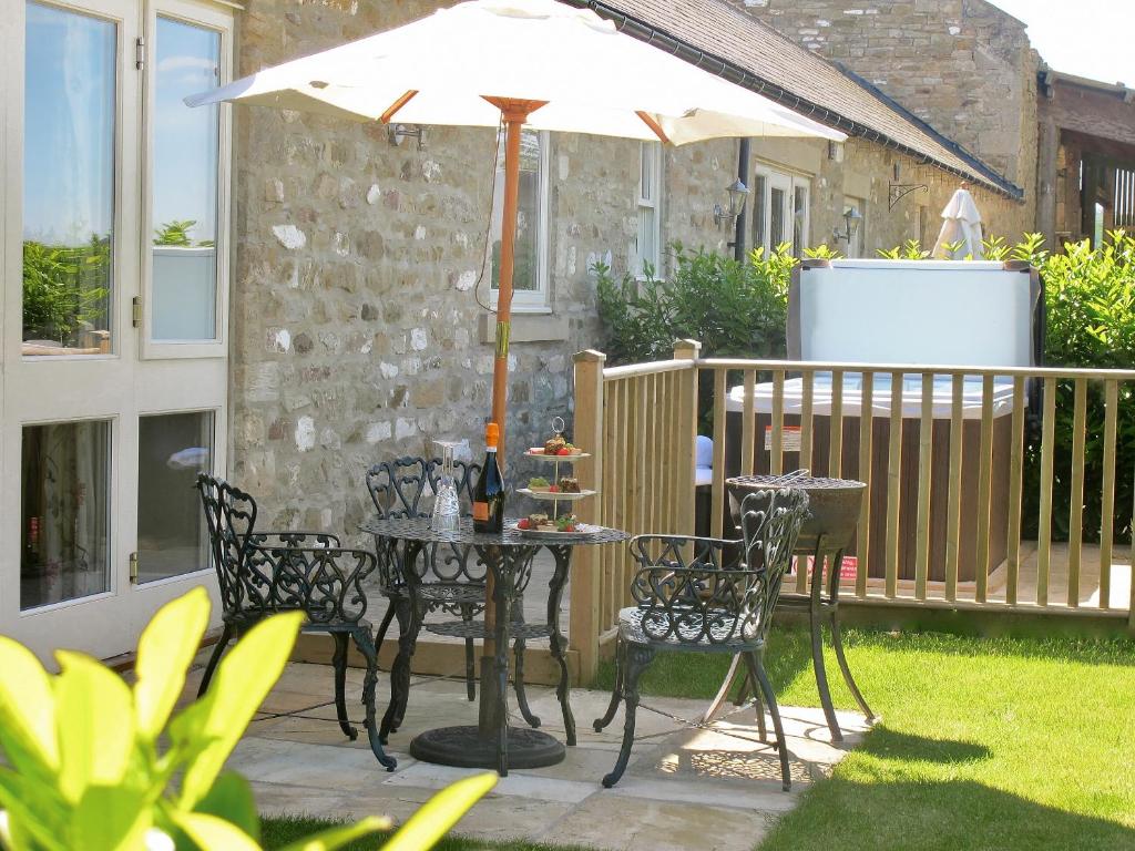 een tafel en stoelen met een parasol op een patio bij Sykelands Cottage in Ravensworth