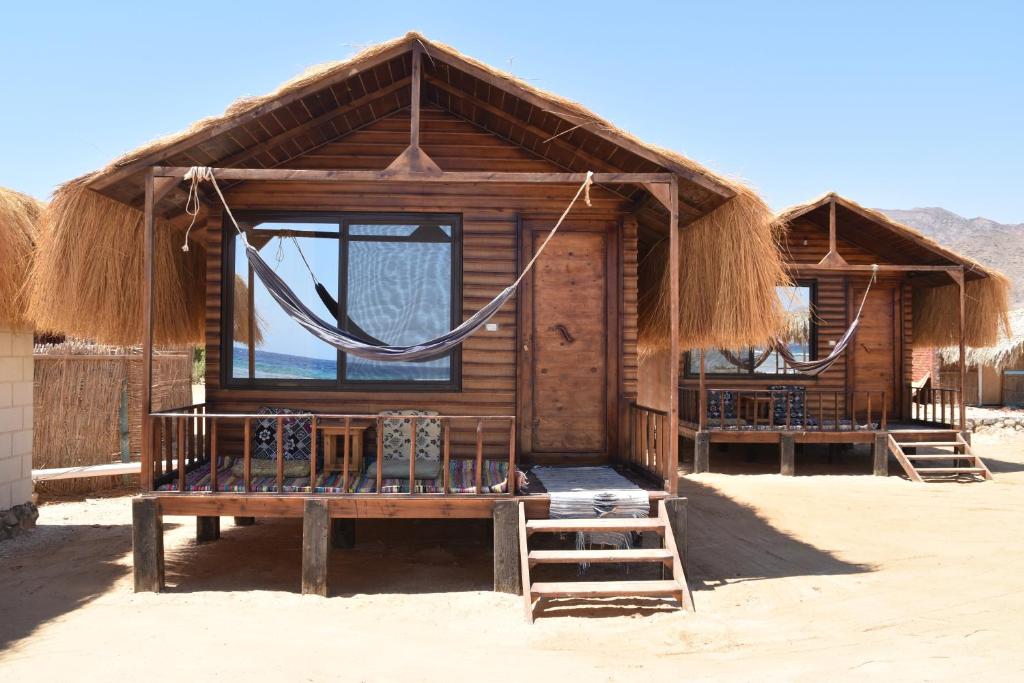 a small cabin with a thatched roof on a beach at Shanty beach camp suer in Nuweiba