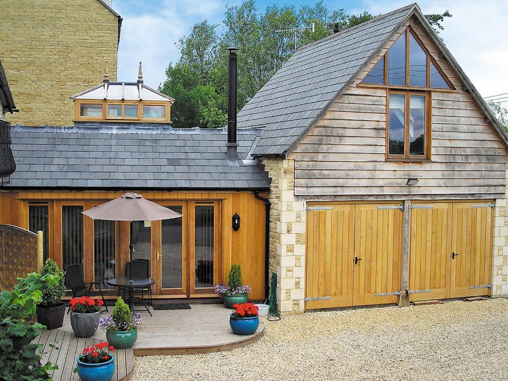 a large wooden garage with a table and an umbrella at Stratton Mill in Cirencester