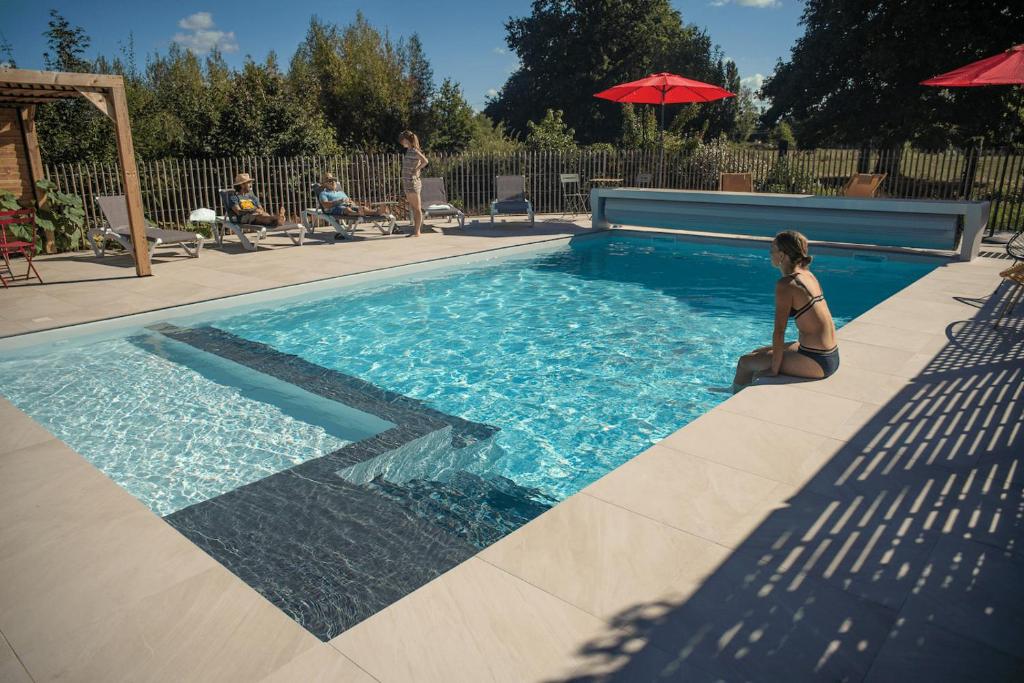 Una donna in bikini seduta accanto alla piscina di Le jardin des 4 saisons a Le Mans