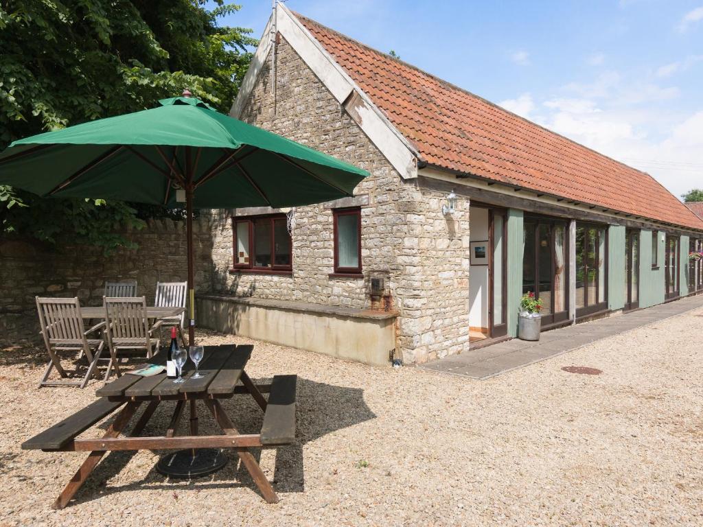 a picnic table with a green umbrella in front of a building at Bramble Cottage in Radstock