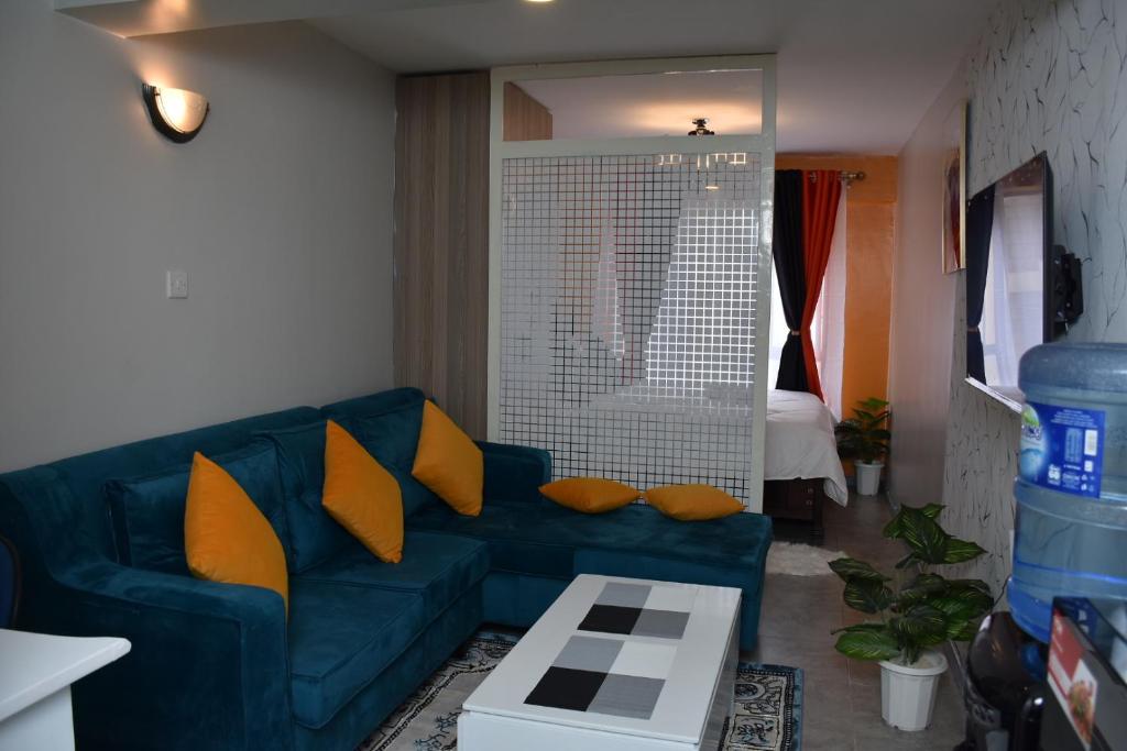 sala de estar con sofá azul y almohadas amarillas en Tsavo Studio Lavish Home-307 en Nairobi