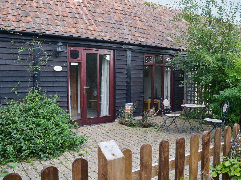 a small house with a red door and a patio at Thyme - E4485 in Ludham