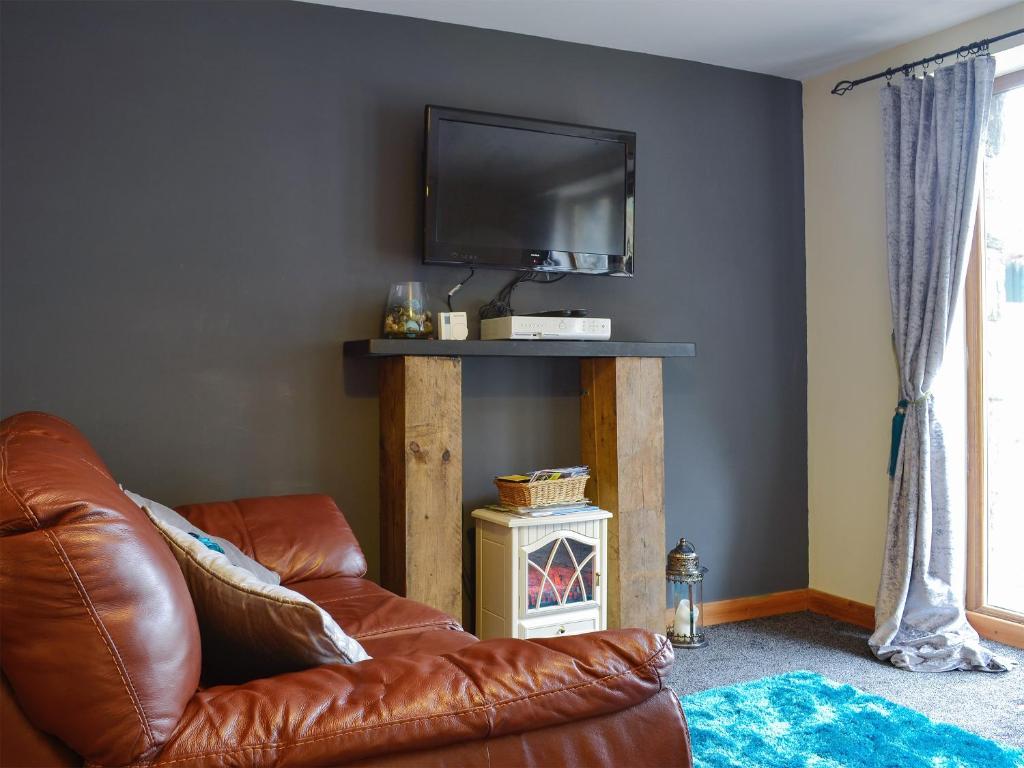 un soggiorno con divano in pelle marrone e TV di Llwyn Rhedyn a Blaenau Ffestiniog