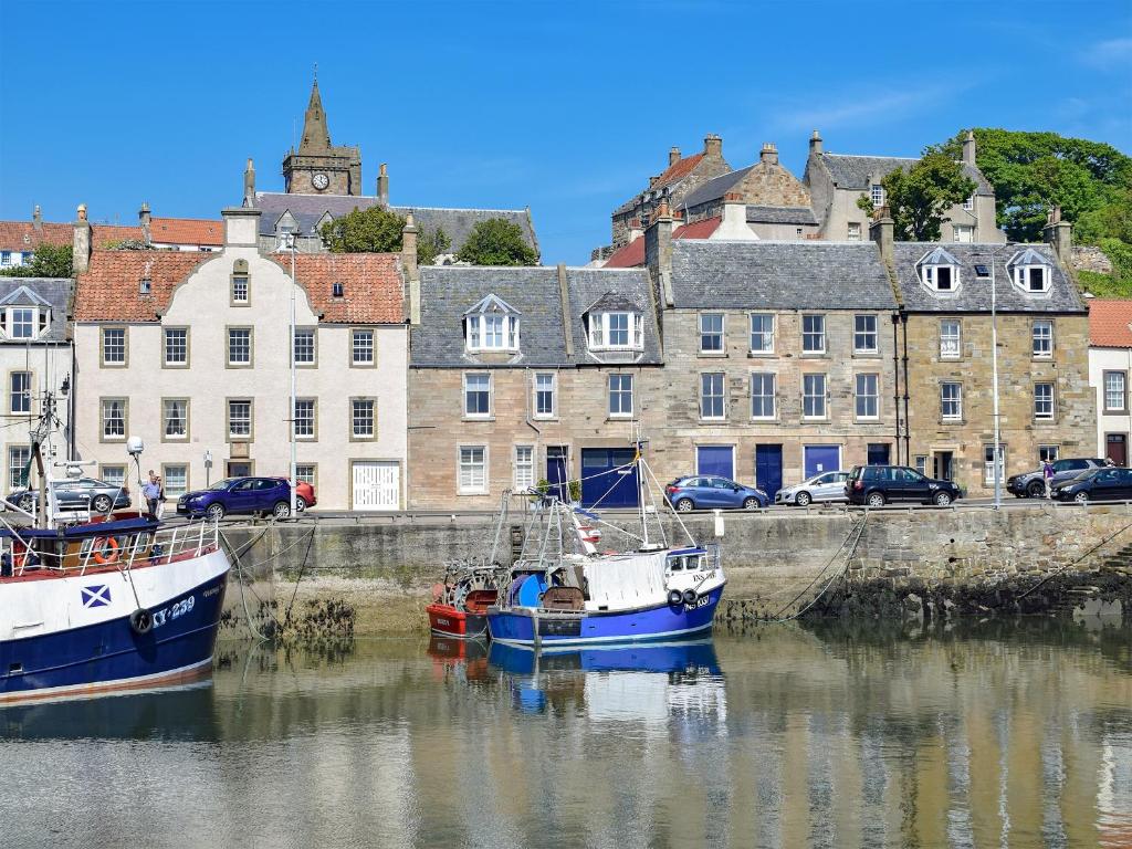two boats docked in the water in front of buildings at St Andrews in Pittenweem