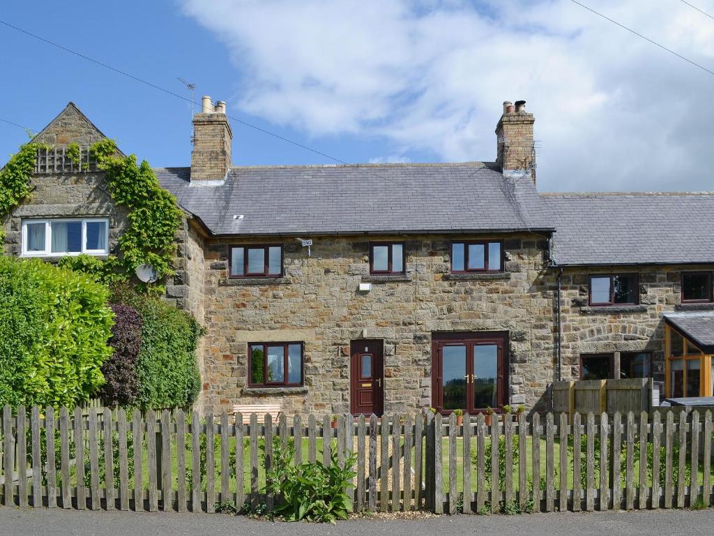 a brick house with a fence in front of it at Sea View in Shilbottle