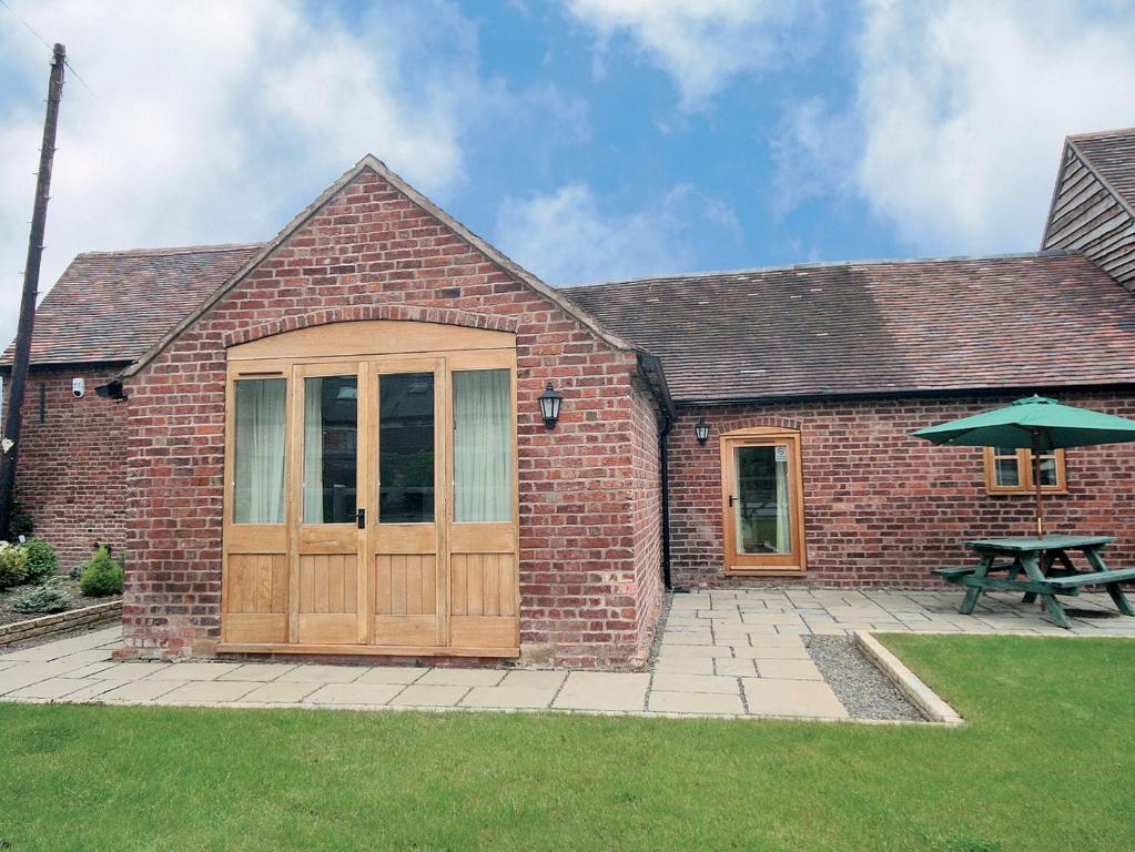 a brick building with a wooden door and a picnic table at Shippon Cottage - E4299a in Halston