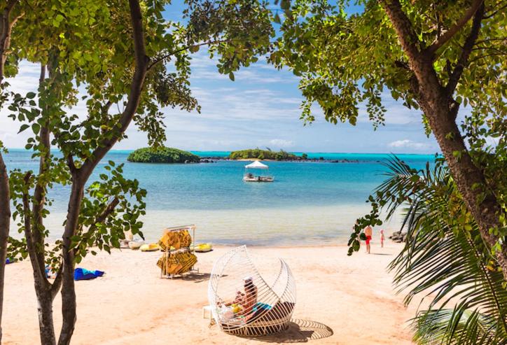 una spiaggia con persone sedute su un'amaca sulla sabbia di Luxury room by Grand Vacations a Roches Noires