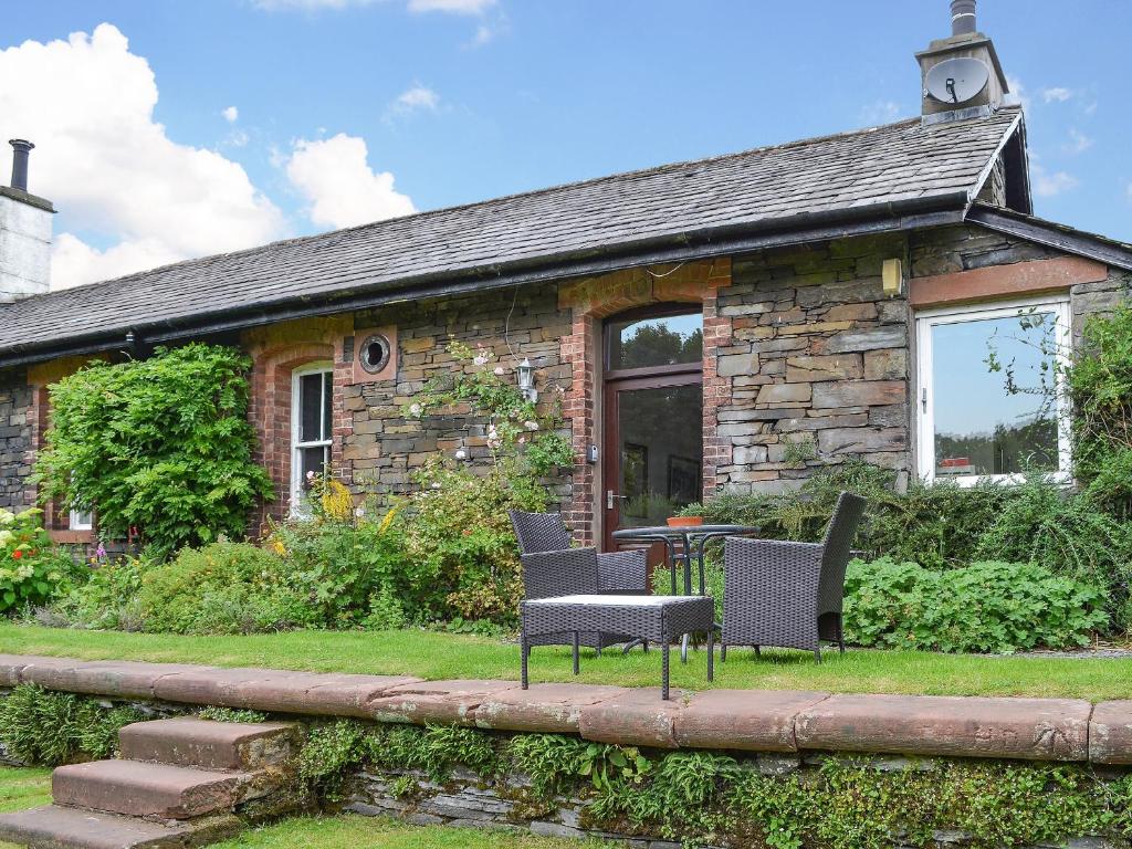 a stone cottage with chairs and a table in front of it at Ticket Office in Torver