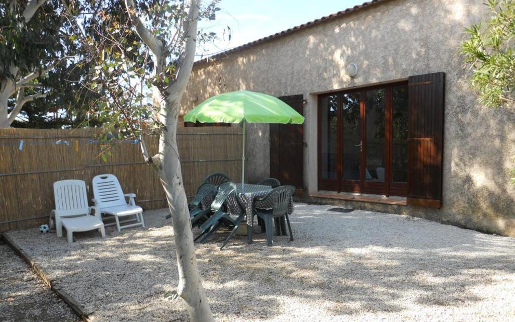 a patio with a table and chairs and a green umbrella at Les lauriers in Hyères