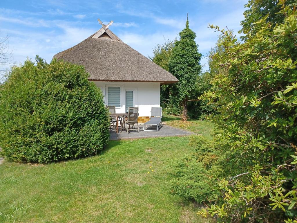 a thatch roofed cottage with a table and chairs at Ferienhaus Ankerplatz 2 in Dierhagen