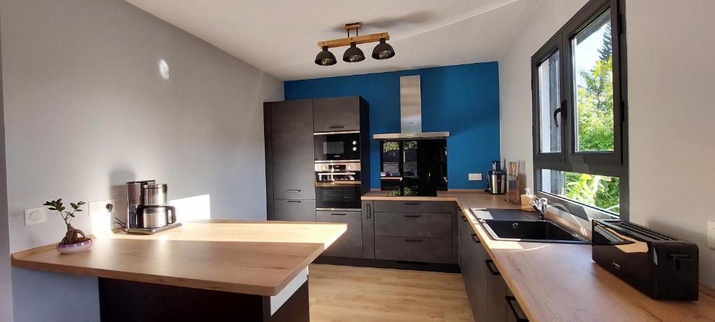 une cuisine avec des murs bleus et un comptoir en bois dans l'établissement La villa Tortue, meublé de tourisme 4 étoiles, à Le Tampon