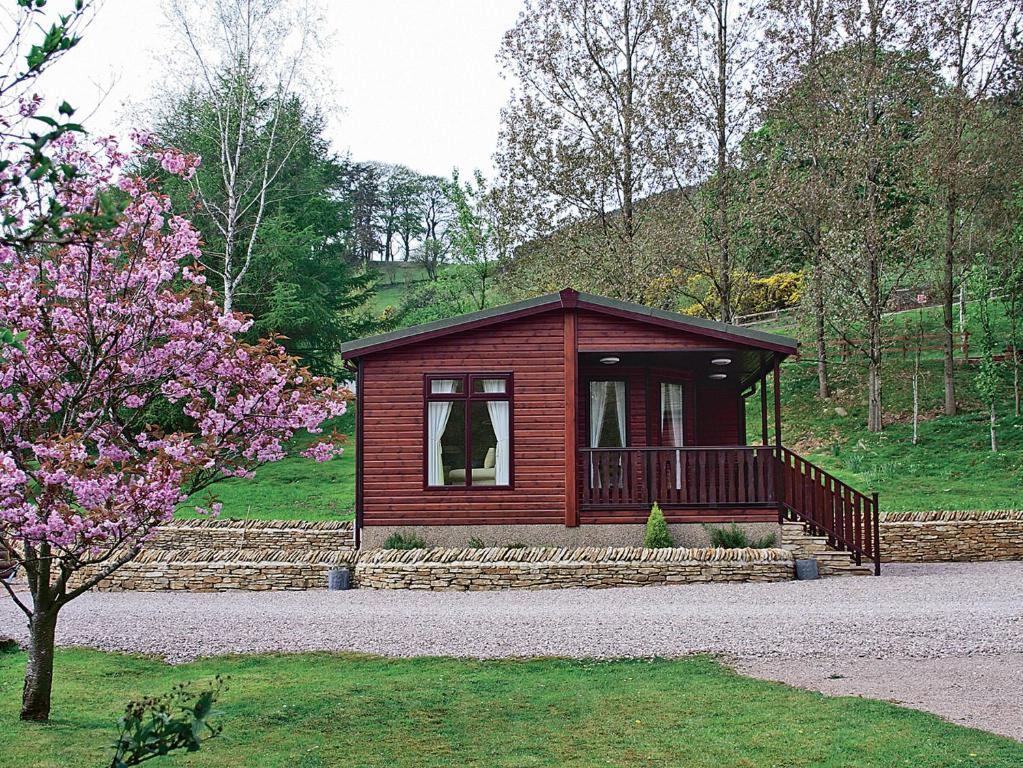 a small cabin in a park with a flowering tree at Hollys Lodge - E4072 in Brough