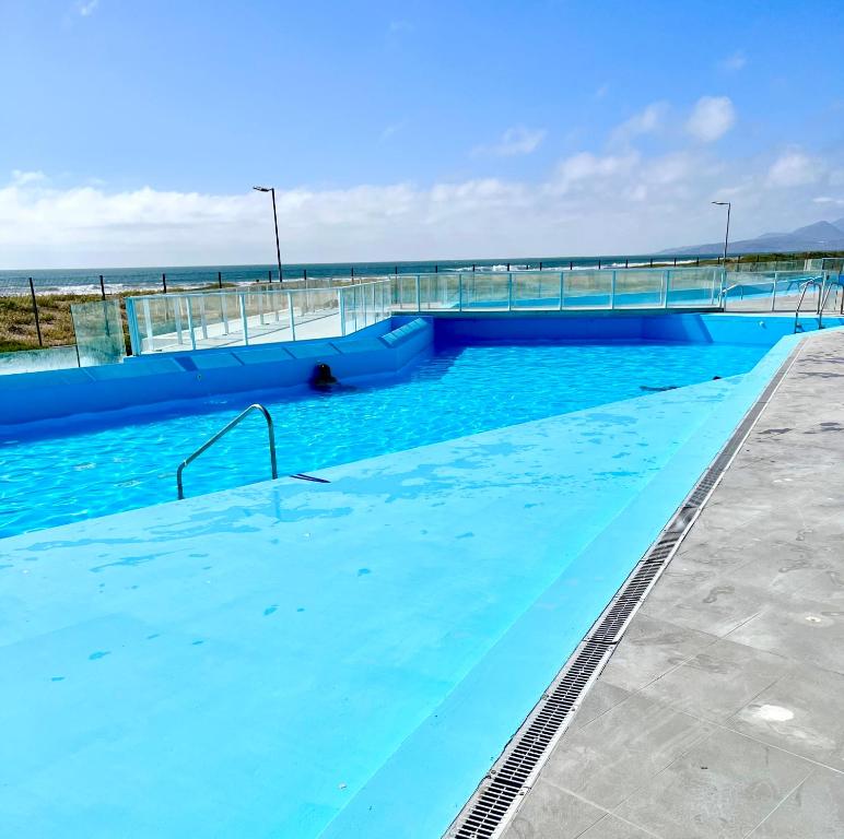 a swimming pool with blue water and a bridge at Laguna del Mar, acogedor Depa para 6 in La Serena