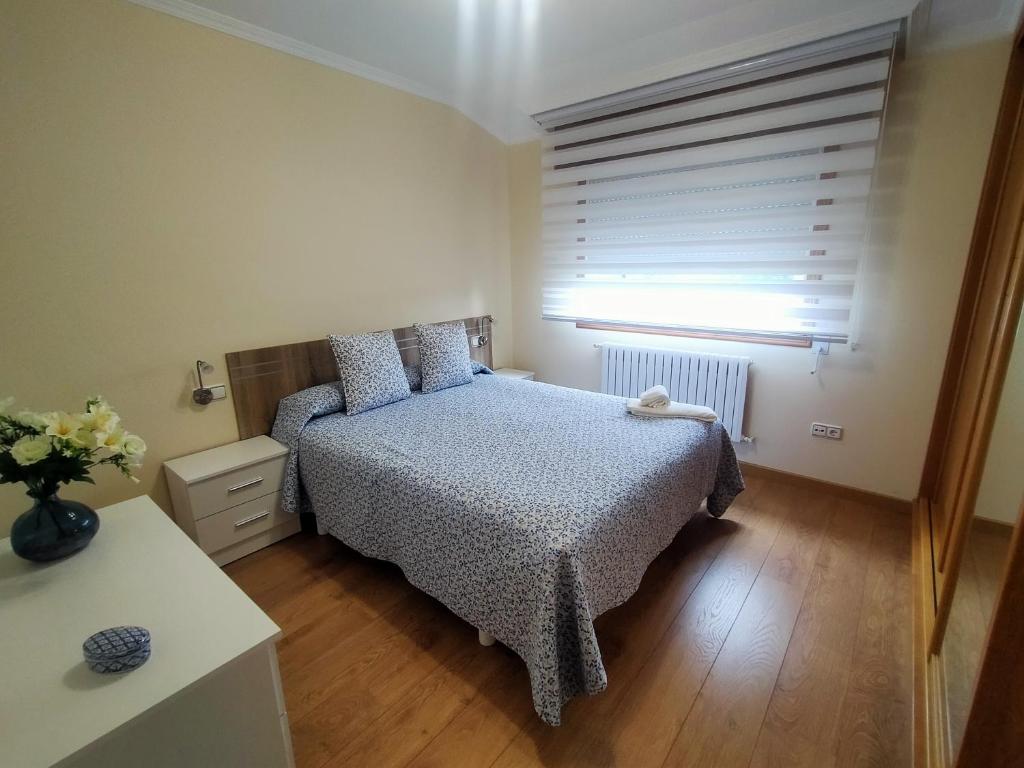 a small bedroom with a bed and a window at Casa Abeleira in Arzúa