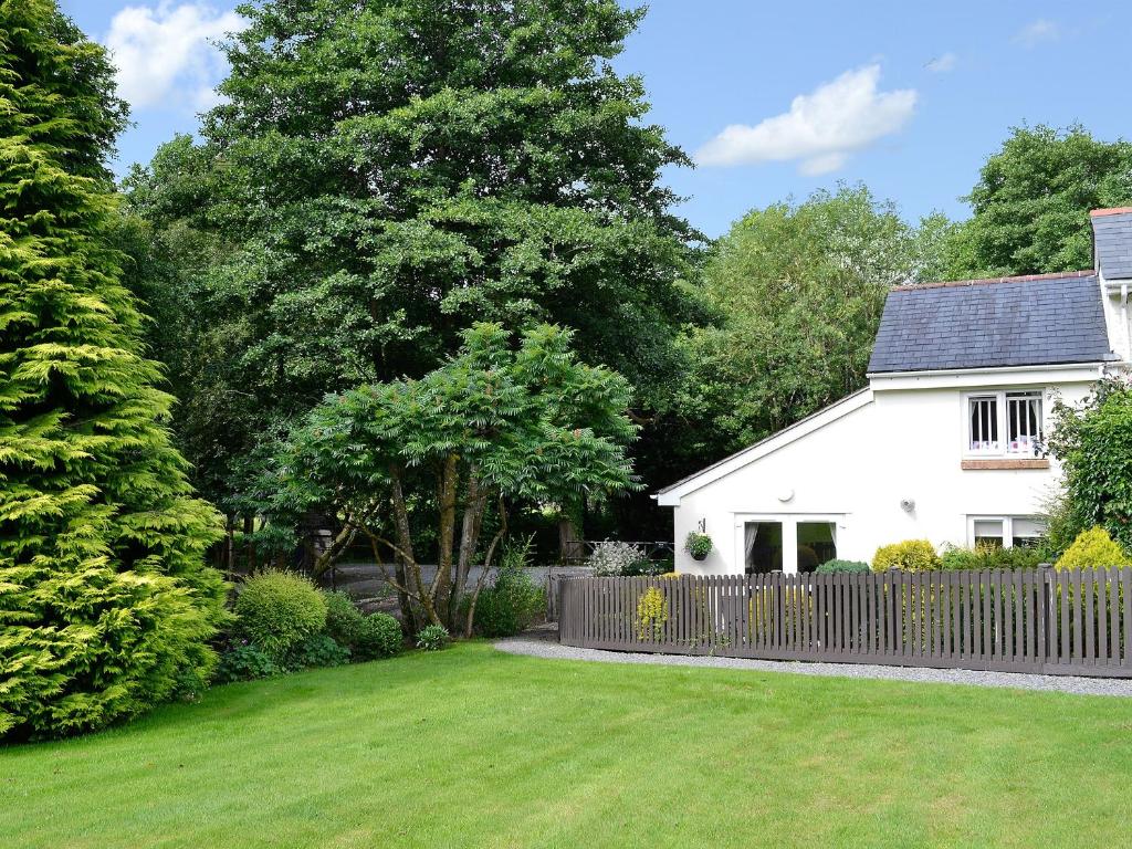 una casa blanca con una valla y un patio en Mole en Swimbridge