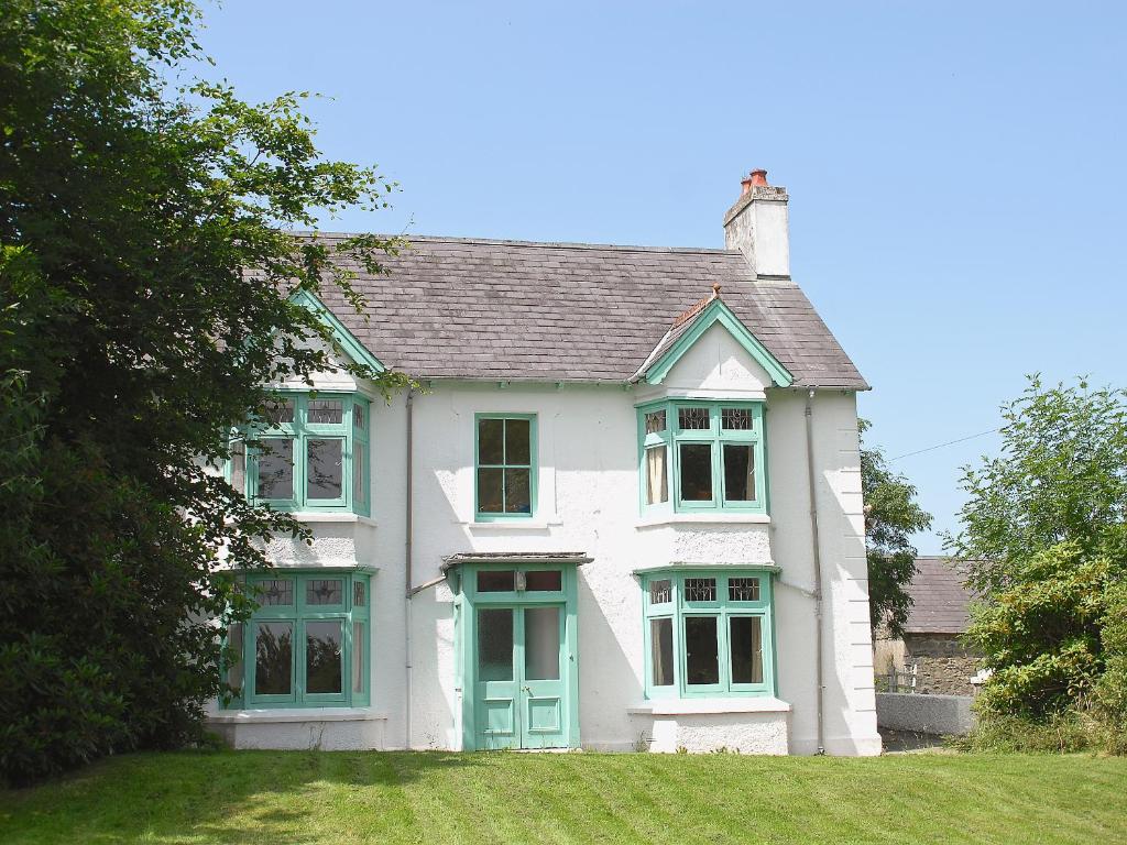 a white house with green windows and a yard at Rwgan in New Quay