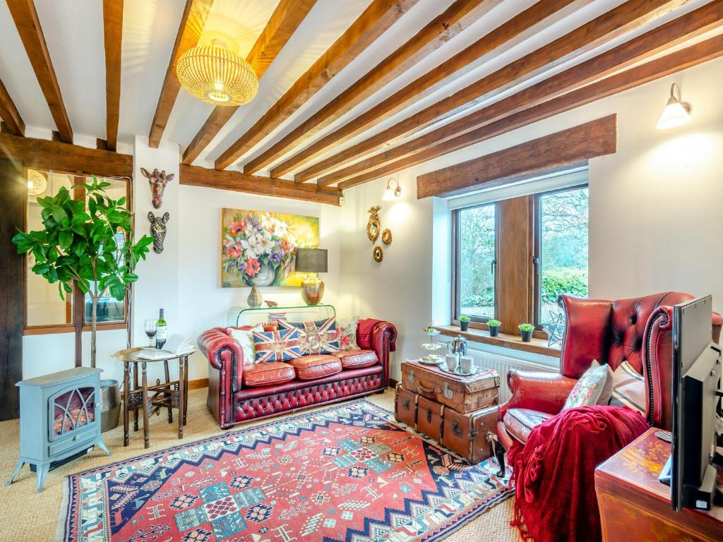 a living room with red furniture and a wooden ceiling at The Cottage in Arminghall