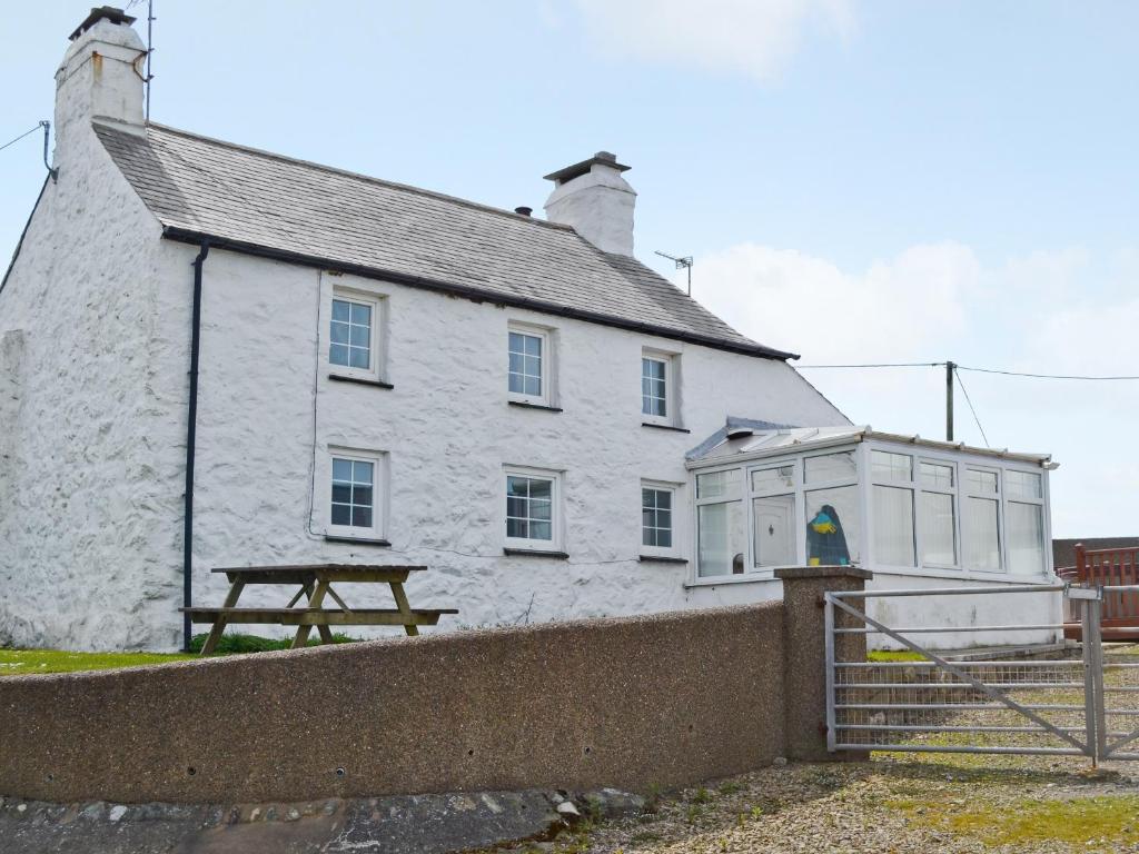 a white building with a picnic table in front of it at Porth Cormon Farmhouse in Llangwnadl