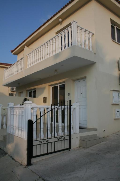 a white house with a balcony and a gate at Nissi Villa in Ayia Napa