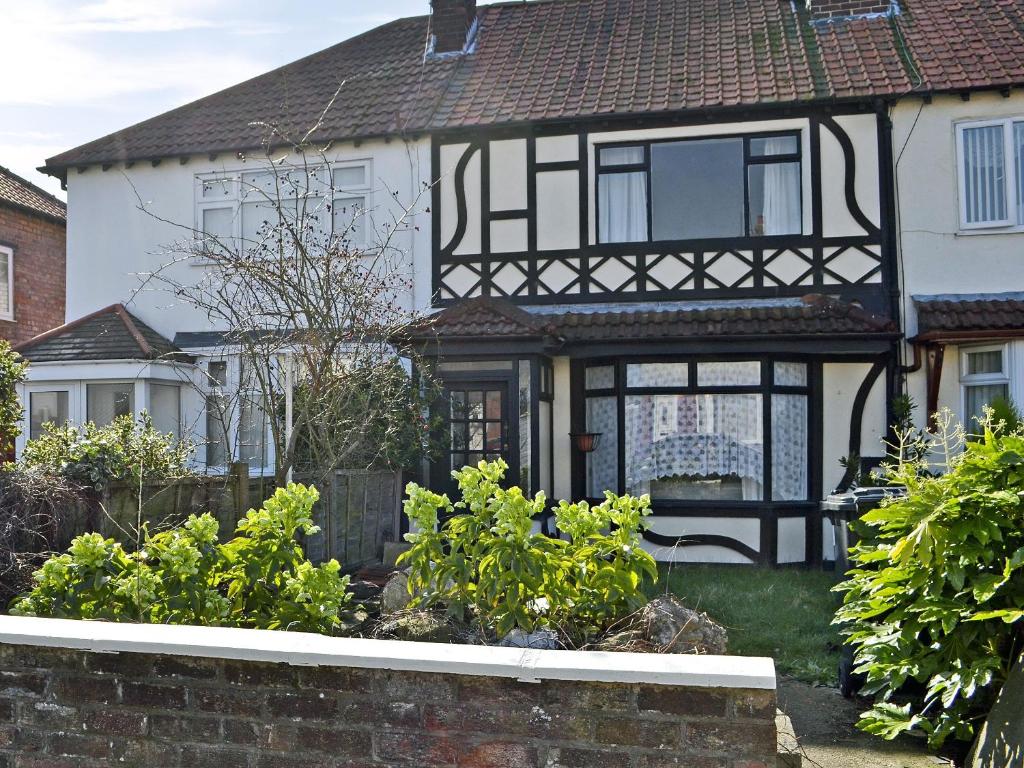 a white and black house with a fence and some plants at Tudor Cottage in Ainsdale