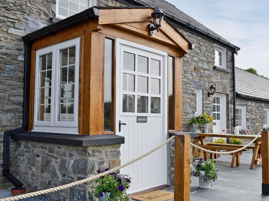 a cottage with a white door and a wooden roof at Golygfar Mynydd - Mountain View in Strata Florida