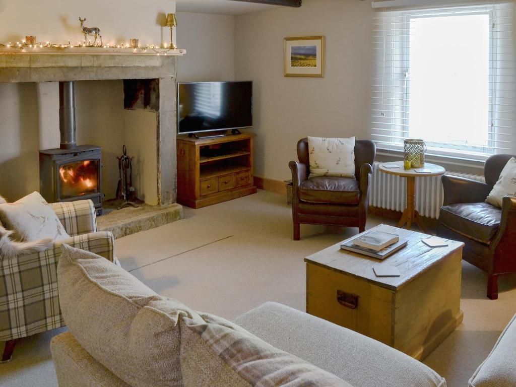 a living room with a fireplace and a tv at West End Cottage in Whittingham