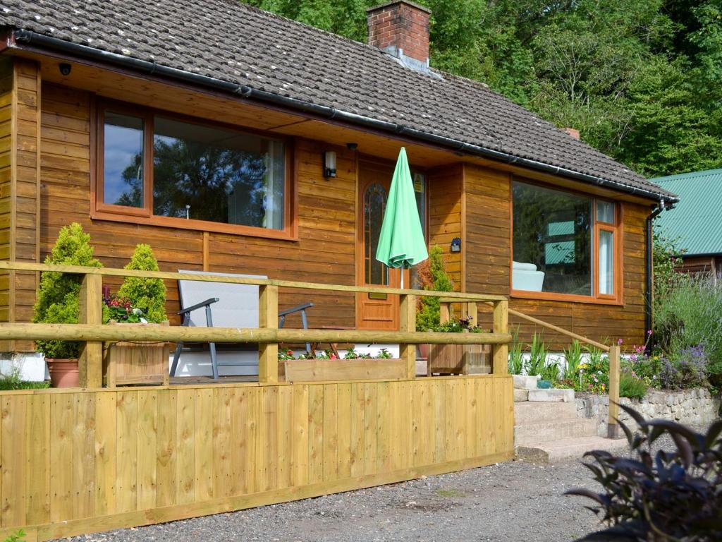una casa in legno con recinzione e ombrellone di Bryn Rodyn a Llanfair-Dyffryn-Clwyd