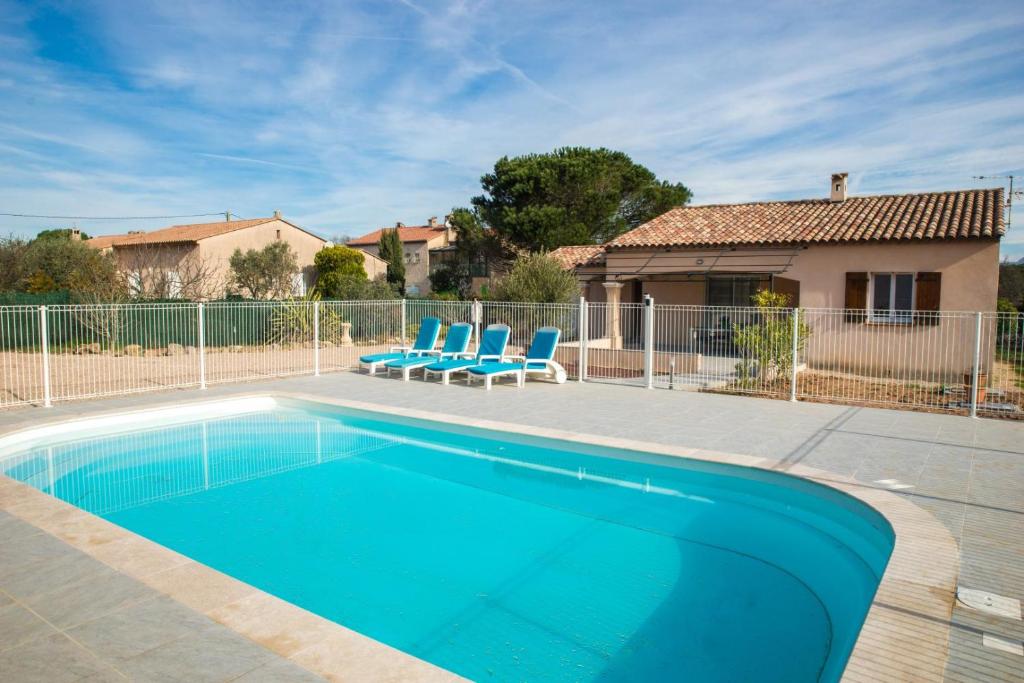 une piscine avec deux chaises bleues et une maison dans l'établissement Gite crovi le muy, au Muy