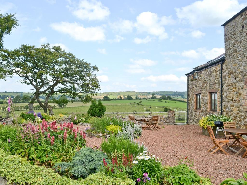 a garden in front of a building with tables and chairs at Ellen Cottage in Ireby