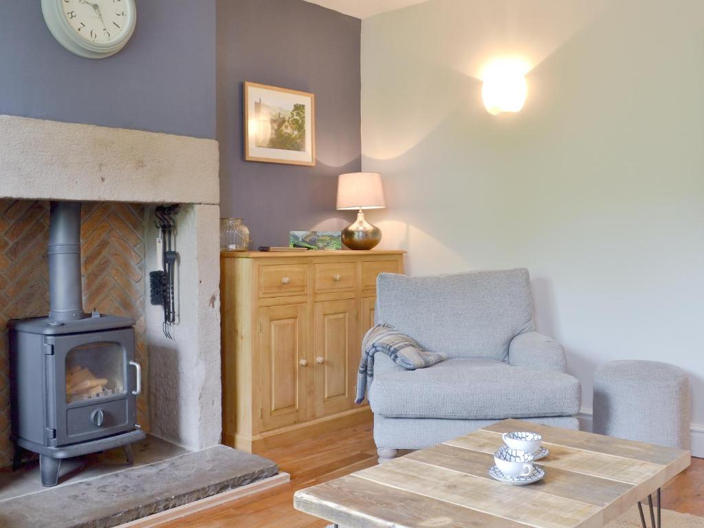 a living room with a wood stove and a chair at Pear Tree Cottage in Wirksworth