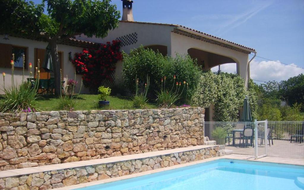 une maison avec un mur en pierre et une piscine dans l'établissement La cigaline, à Bagnols-en-Forêt