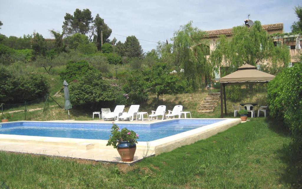 a swimming pool with chairs and a gazebo at Villa la desirade in Cotignac