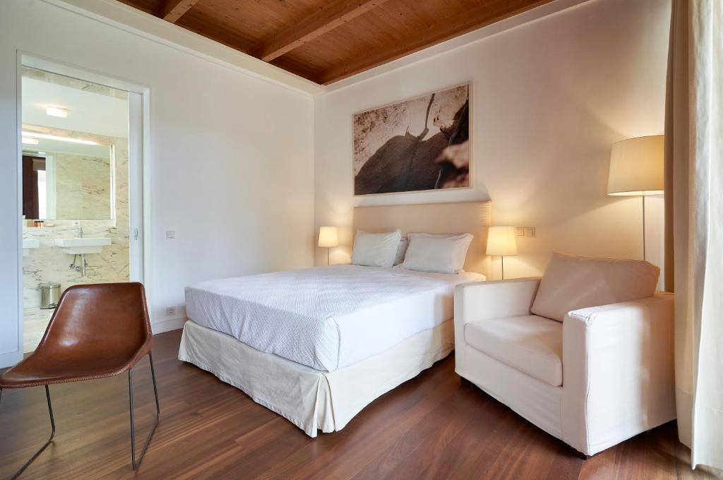 a bedroom with a white bed and a chair at Hotel Porto Santo & Spa in Porto Santo
