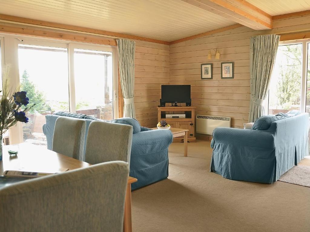 a living room with blue couches and a television at Hawthorne in Woolfardisworthy